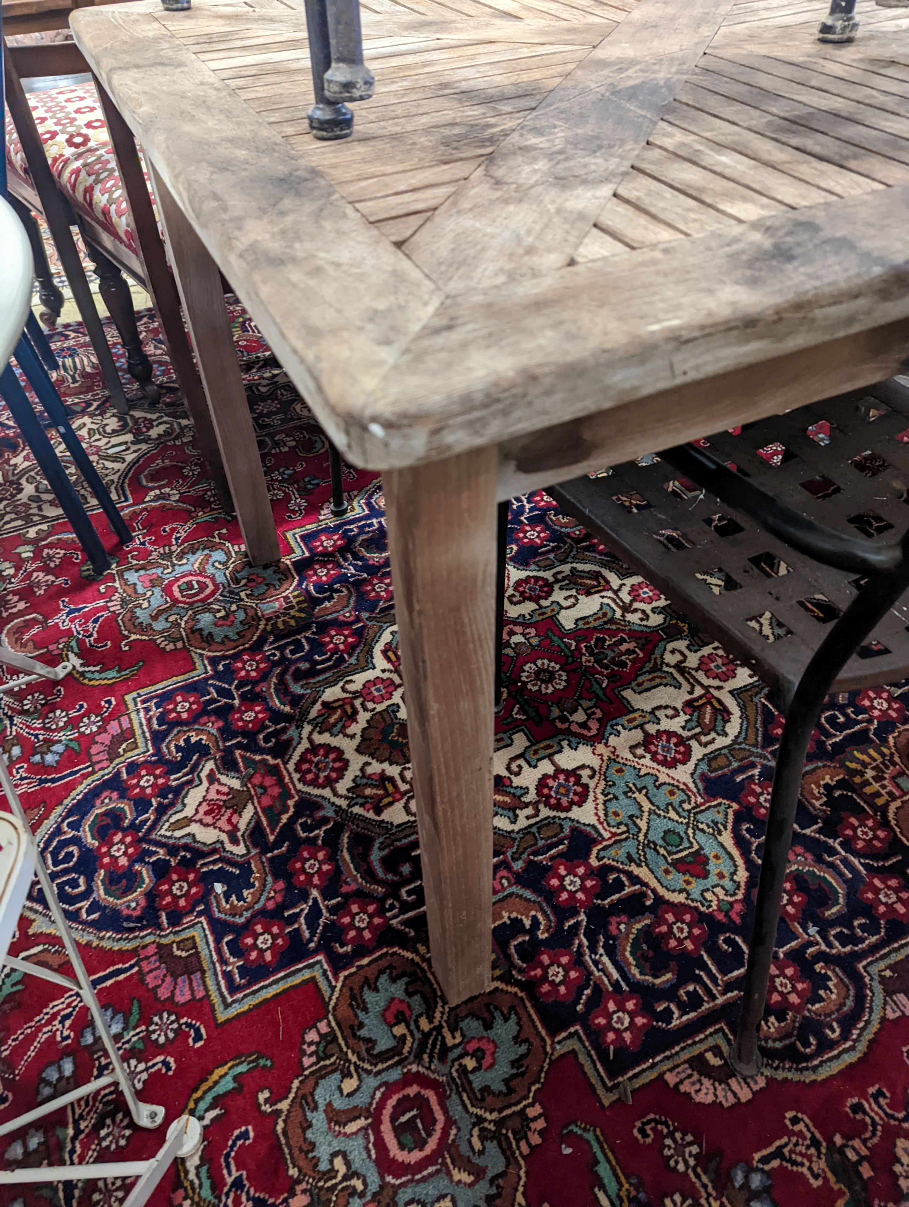 A square teak garden table, width 89cm, height 74cm and four metal garden chairs